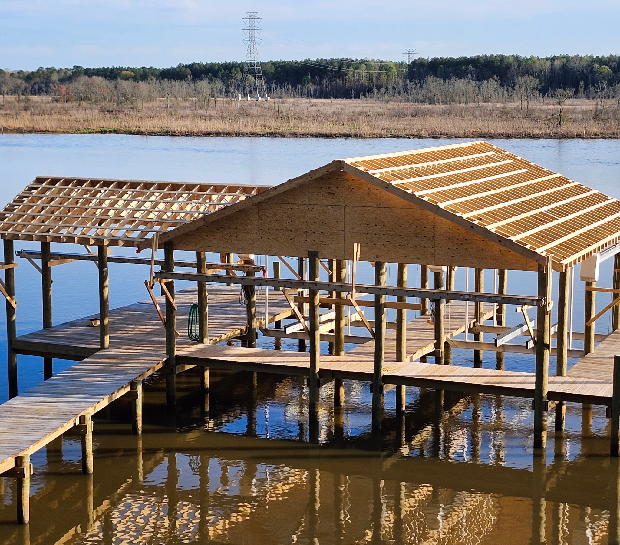 Wide view of a timber boathouse and dock during roof construction