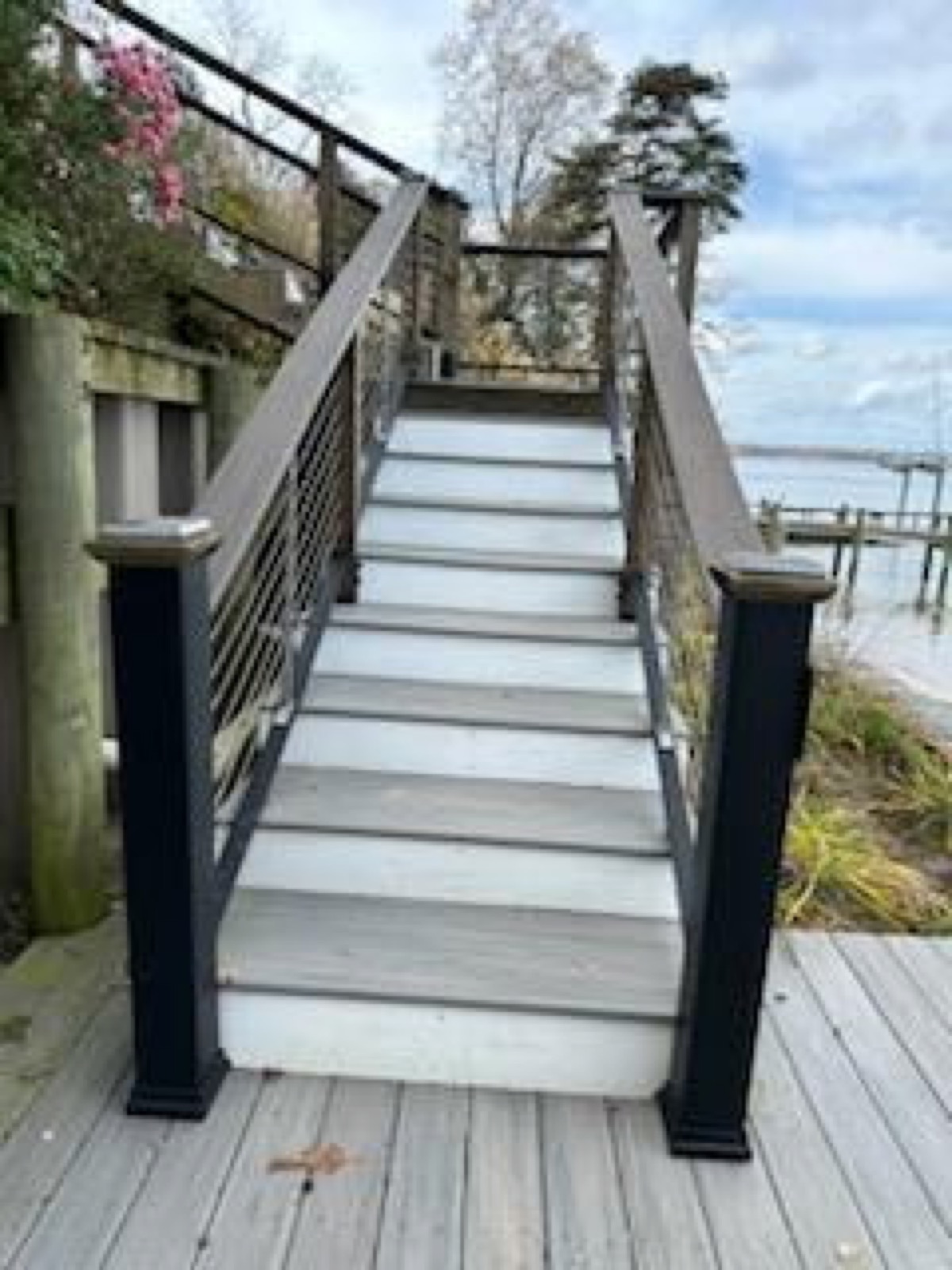 Composite waterfront stairs with dark railings leading toward the water